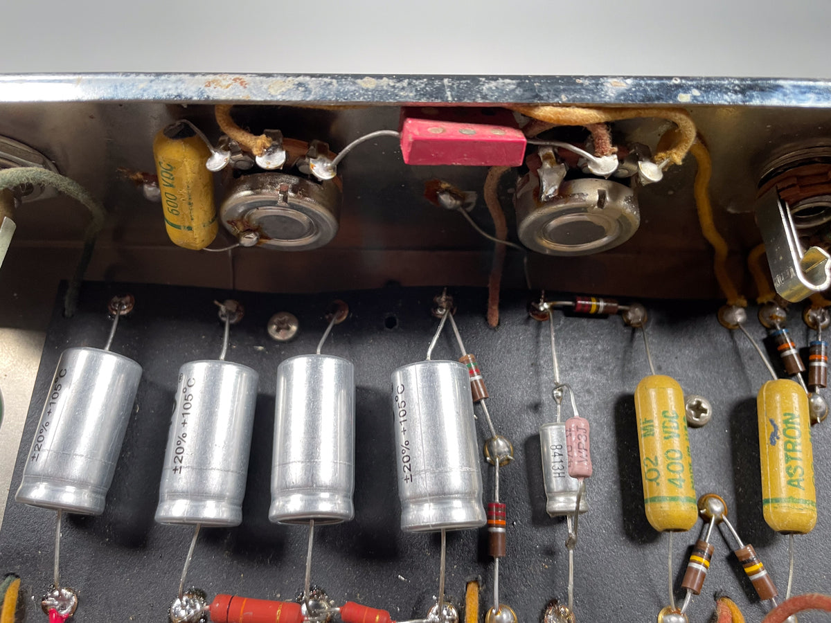 Close-up of the amp's internal wiring and components, showing several silver and yellow capacitors, resistors, and aged wiring.