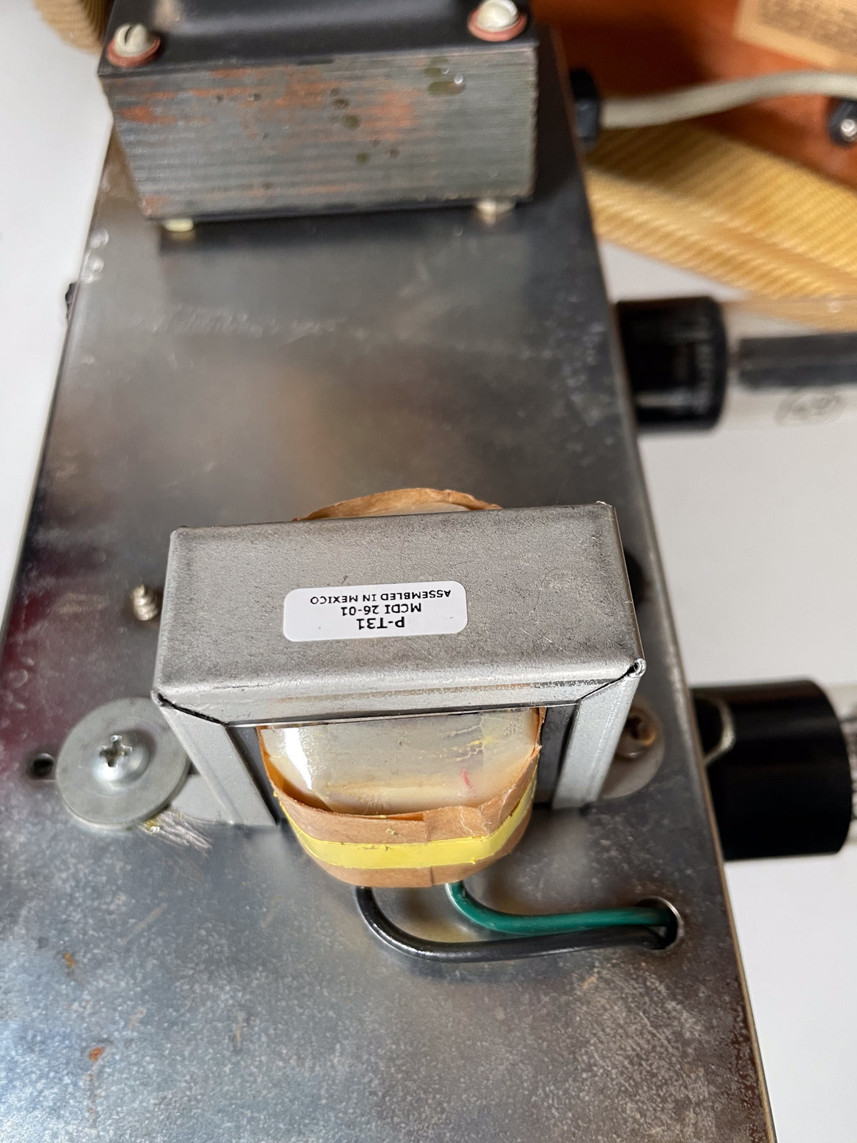 Close-up of the amp's metal chassis, showing a silver transformer with a label, wrapped in yellow and brown tape, with green and black wires.