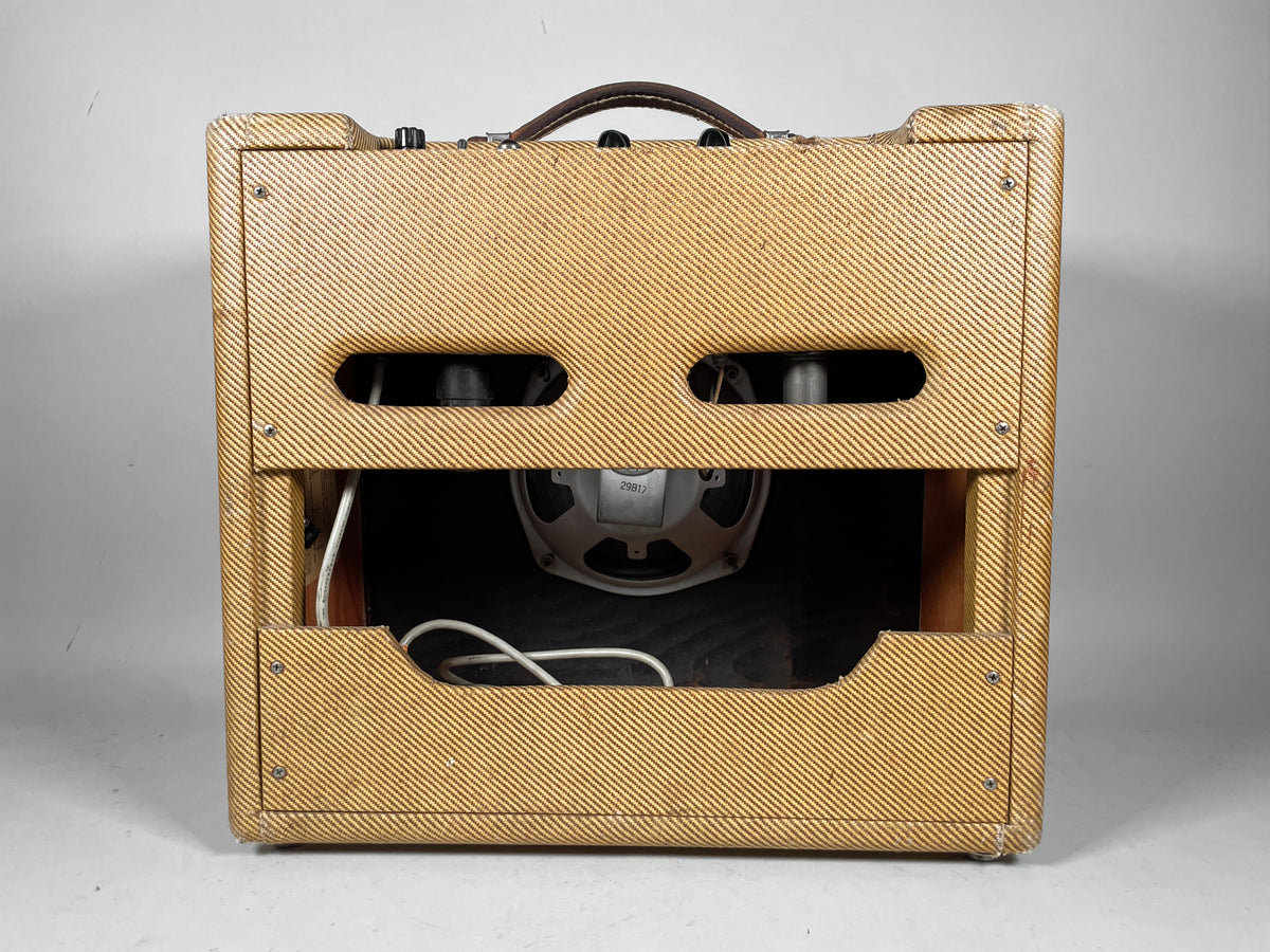 Rear view of the tweed combo amp, showing the open back with a visible speaker, tubes, and some wiring.
