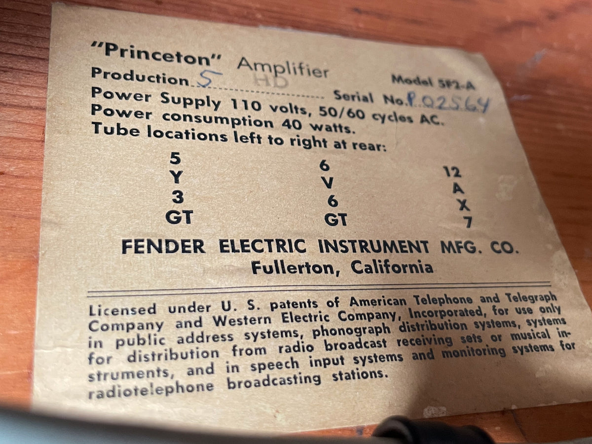 Close-up of the amp's light brown paper label, showing black text and handwritten blue serial number.