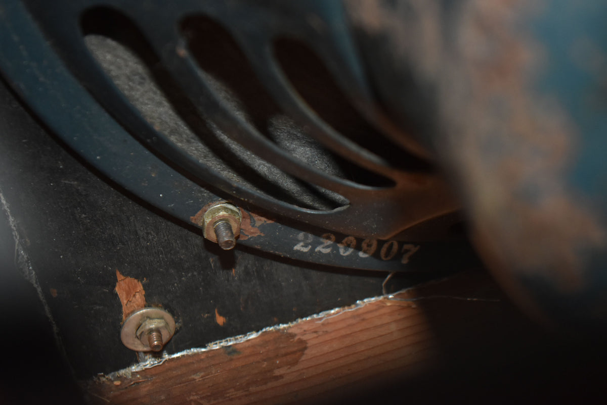 Close-up of the amp's black speaker frame with visible rust on the mounting bolts, worn tolex, and the serial number 220907.