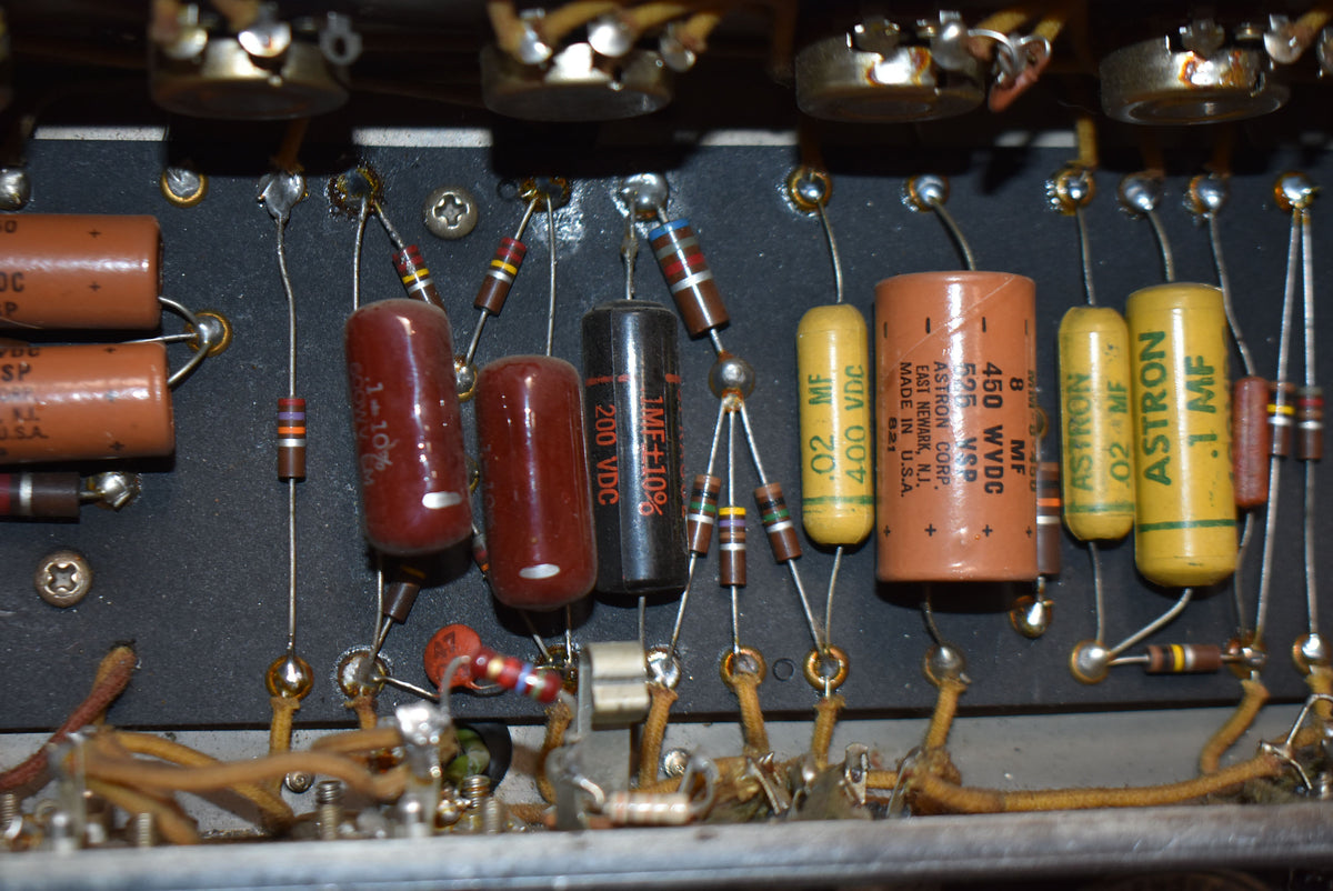 Close-up of the amp's internal wiring, showing various brown, black, and yellow capacitors and resistors soldered to a dark board.