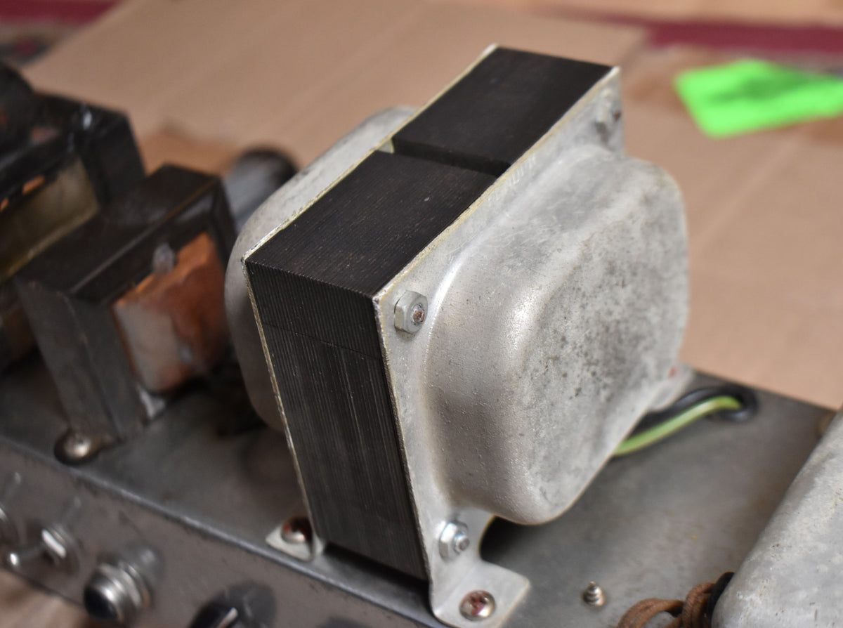 Close-up of the amp's internal components, showing a large, dusty silver transformer with black laminations, bolted to a metal chassis.
