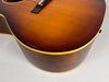 Close-up of the guitar's lower bout, showing the sunburst top, dark sides, cream binding, and notable finish wear and scratches.