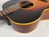 Close-up of the sunburst acoustic guitar's body, showing the dark brown top with wear, light binding, and dark wood sides.