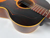 Upper body of a sunburst acoustic guitar, showing a dark tortoiseshell pickguard, heavy finish checking, and binding wear.