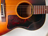 Close-up of the sunburst body, showing the tortoise pickguard, bridge, soundhole, and lower fretboard with visible finish wear.
