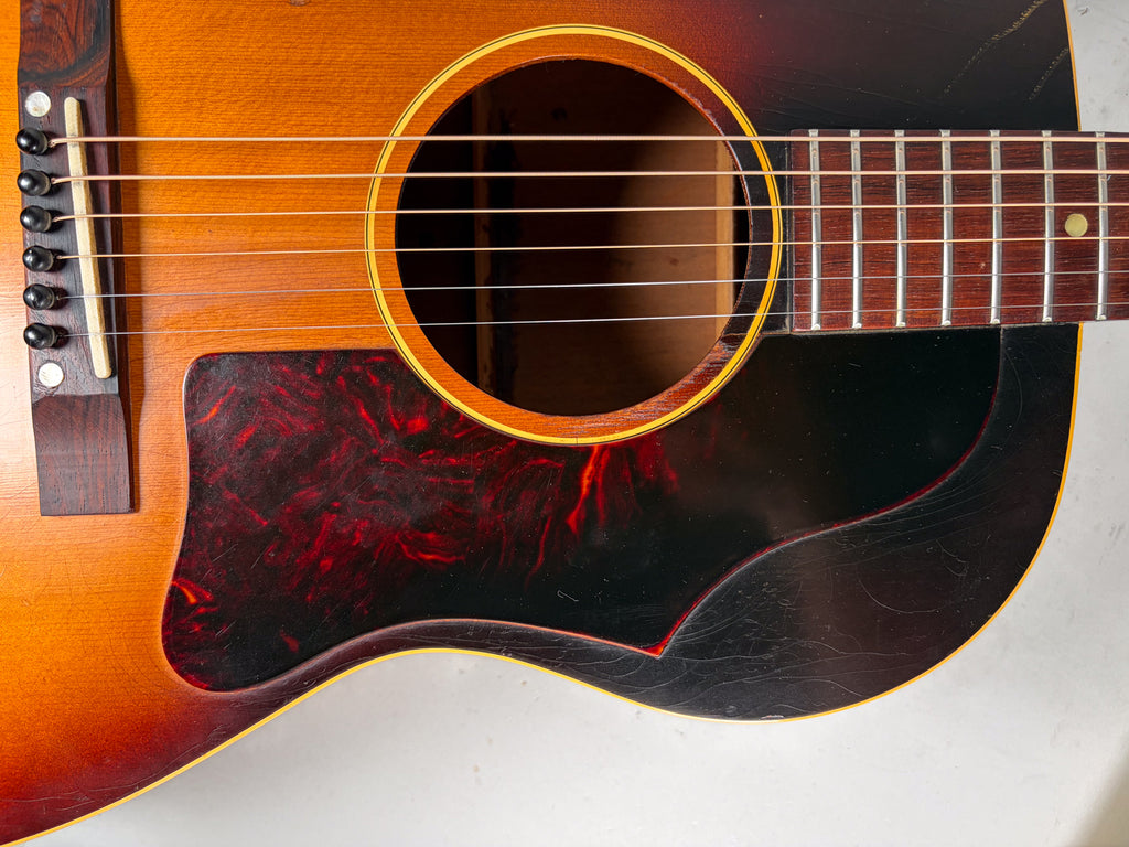 Close-up of the sunburst body, showing the tortoise pickguard, bridge, soundhole, and lower fretboard with visible finish wear.