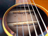 Close-up of the soundhole, showing internal bracing with visible glue residue and wear, plus four light-colored strings.