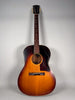 Full-length view of a sunburst acoustic guitar with a dark tortoiseshell pickguard, showing wear and finish checking.