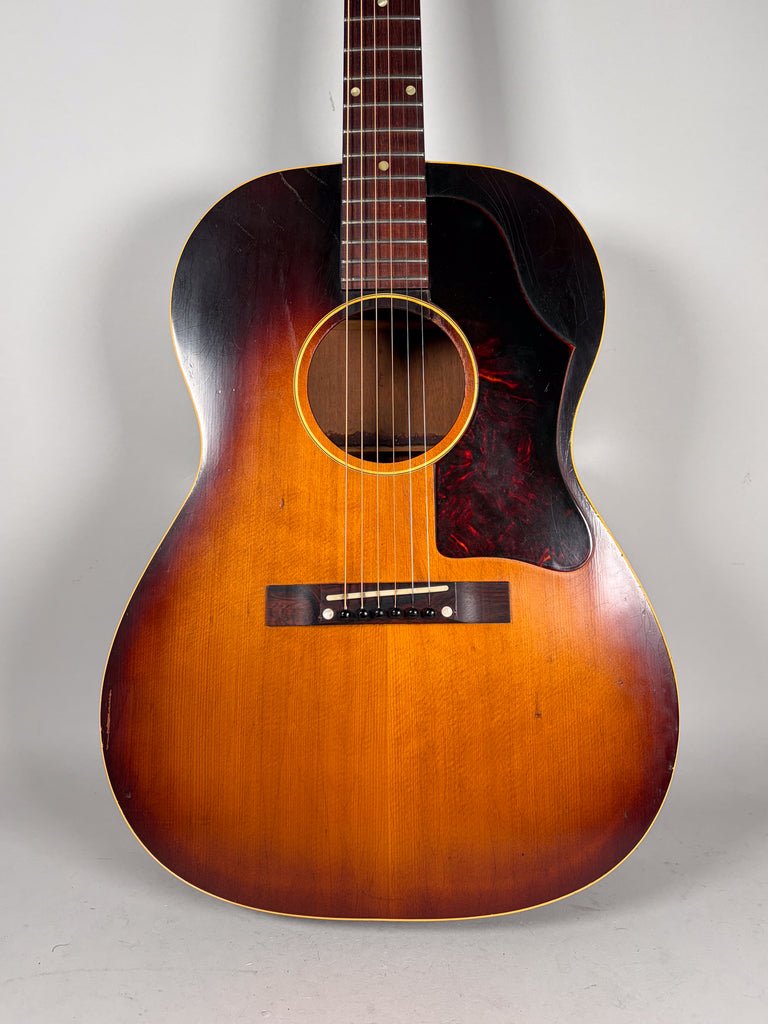 Full-frame view of the sunburst acoustic guitar, showing a dark tortoise pickguard and visible finish checking on the body.