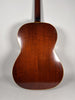 The guitar's dark brown back and neck are visible, with light binding around the body and some minor surface wear.