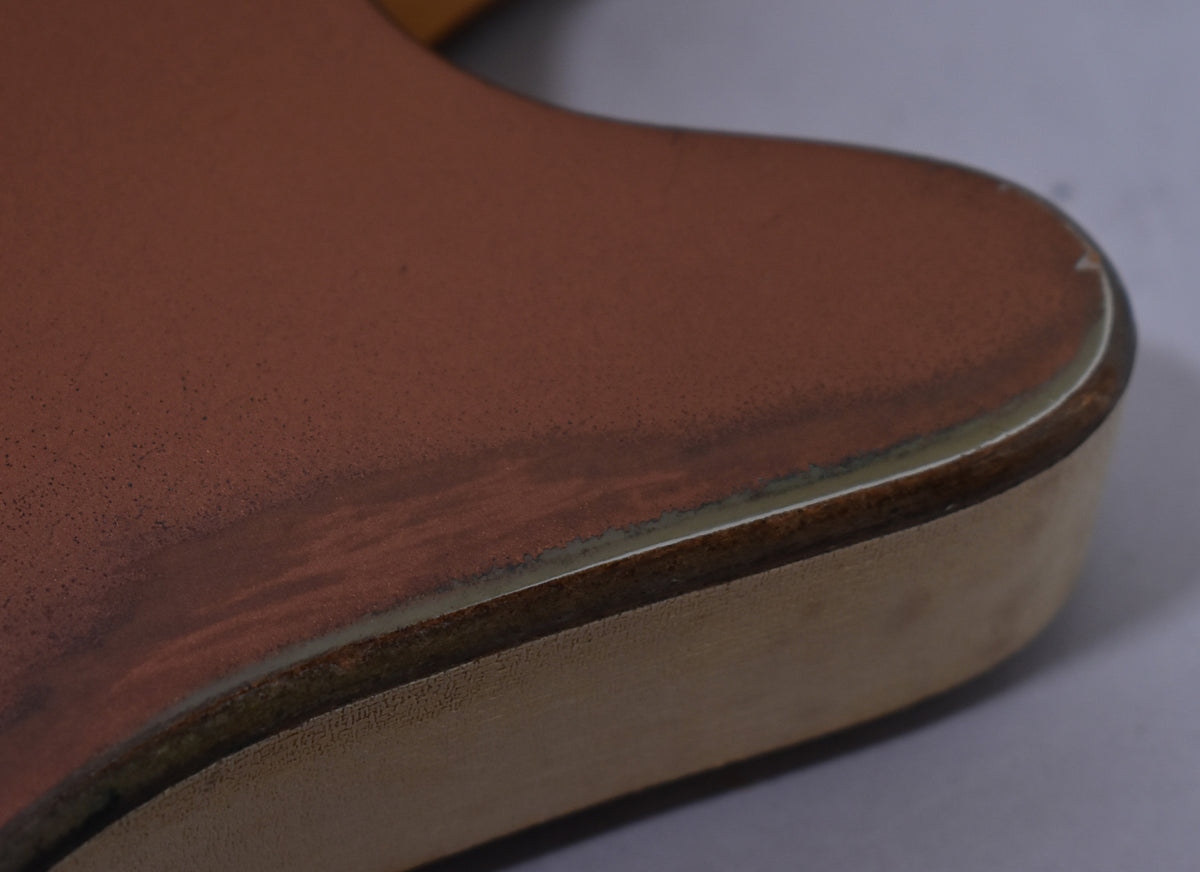 Close-up of the guitar's lower bout, showing the copper finish with visible wear and a cream binding around the edge.