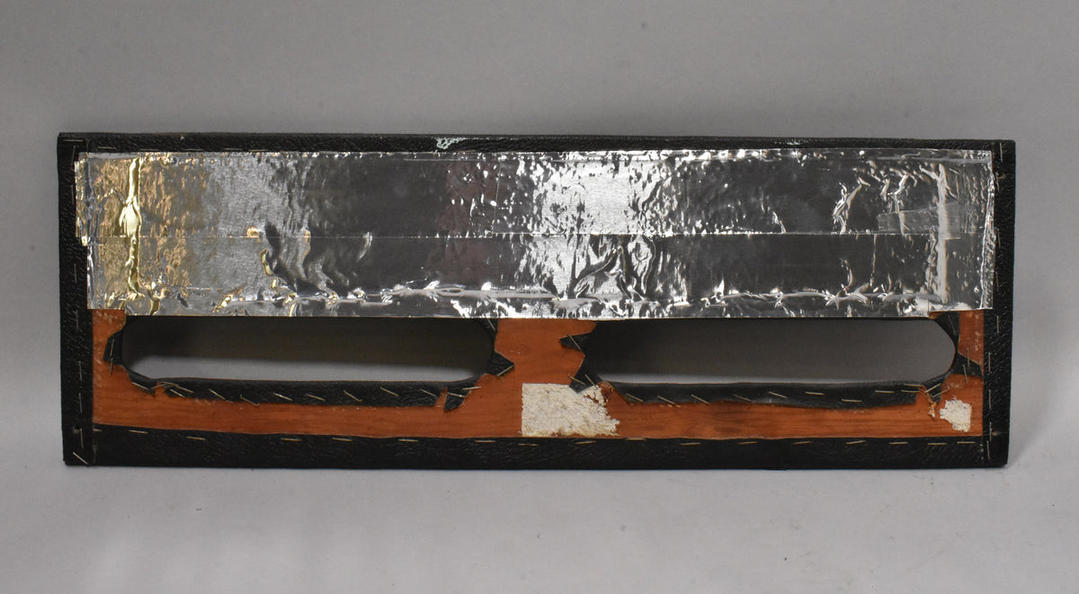 The amp's rear panel, showing two rectangular openings, exposed wood, black tolex, and crumpled silver foil lining.