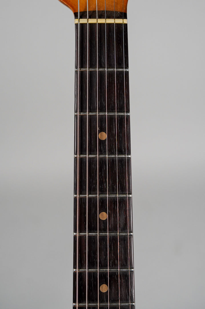 Close-up of the dark rosewood fretboard with light brown dot inlays, showing frets 1-9 and the nut.