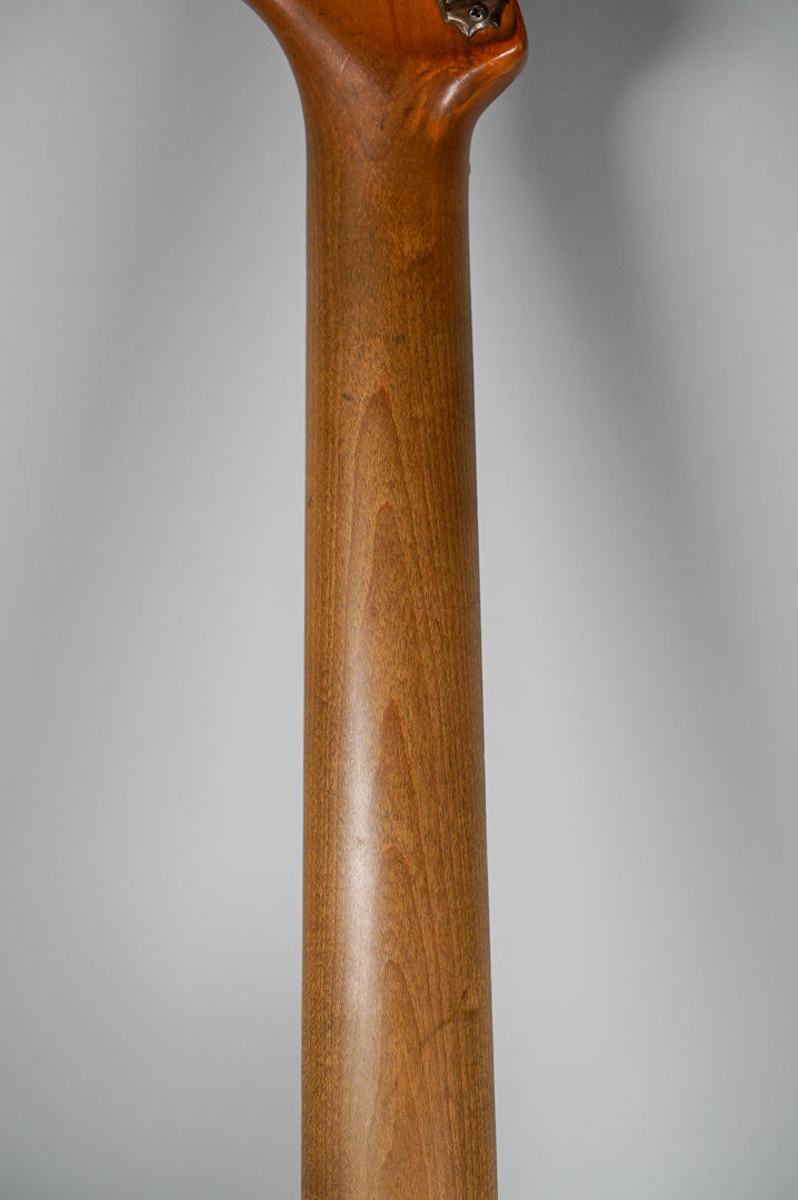 The guitar's neck, a medium brown wood with visible grain, is shown from the back, with some wear near the headstock.