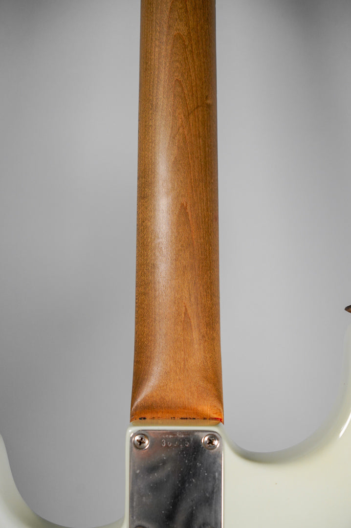 The guitar's neck heel and upper body are visible from the back, showing a worn natural wood neck and white body.