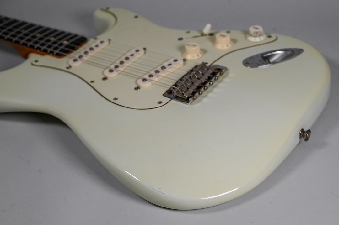 The white refinish Stratocaster body, angled from the neck, shows three cream single-coil pickups, a chrome tremolo, and light wear.