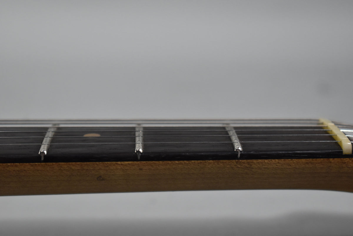 Close-up of the guitar's dark fretboard and light-colored frets, with a cream nut visible on the right.