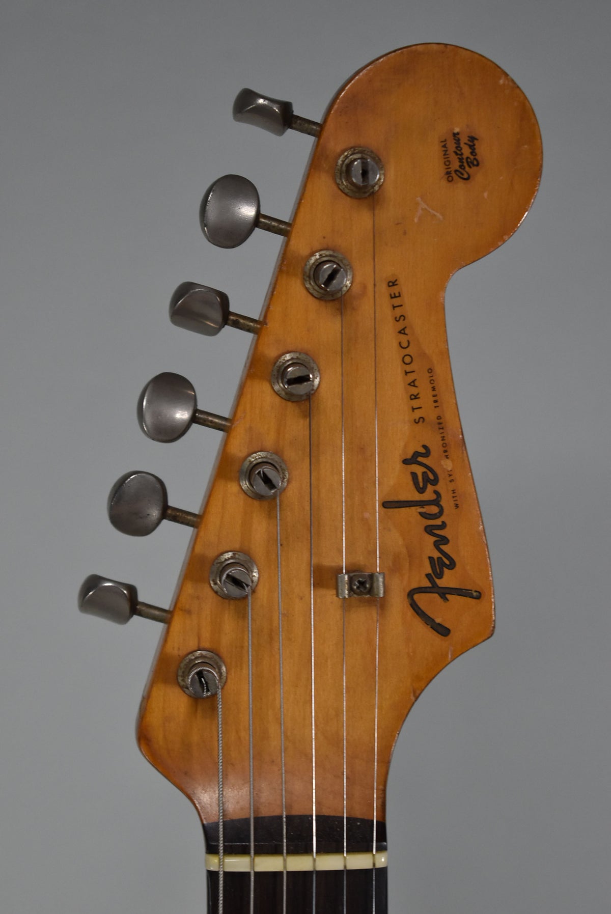 The guitar's headstock, with six metal tuners and a string tree, shows a worn, aged amber finish and visible checking.