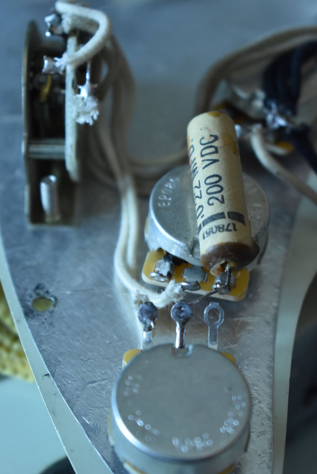 Close-up of the guitar's internal electronics, showing a paper-in-oil capacitor, potentiometers, and cloth-covered wiring.