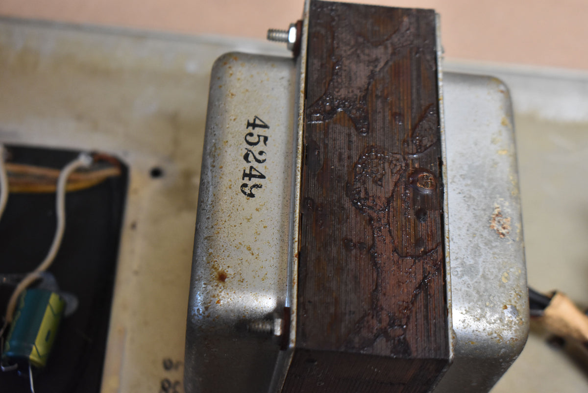 Close-up of a transformer with a dark brown, textured core and a tarnished silver casing with "45249" stamped on it.