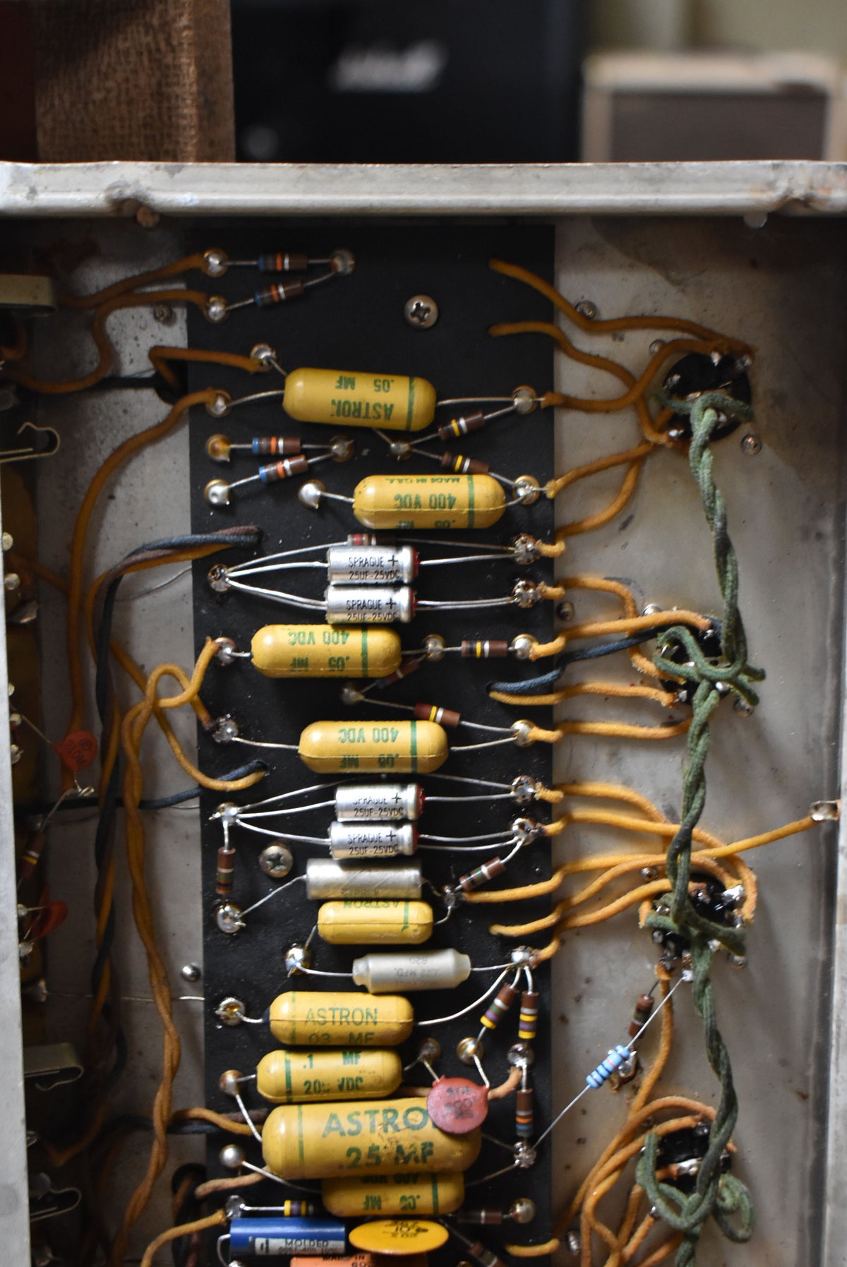 A close-up of the amplifier's internal wiring, showing rows of yellow and silver capacitors, resistors, and orange and green wires.