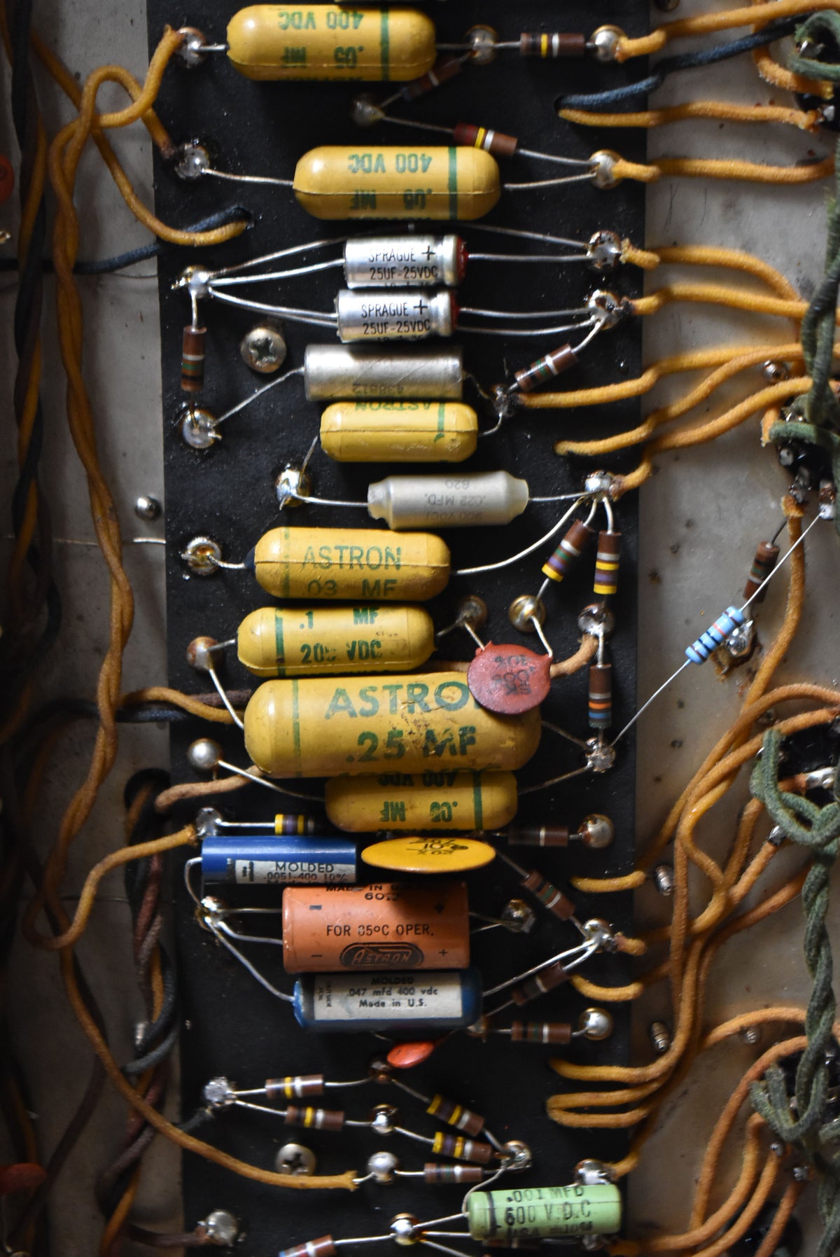 A close-up of the amplifier's internal circuit board, showing rows of yellow, silver, and blue capacitors with various resistors and orange wiring.