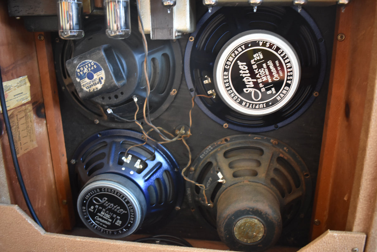 Rear view of the amplifier's four speakers, two with blue frames, showing exposed wiring, vacuum tubes, and a worn wood cabinet.