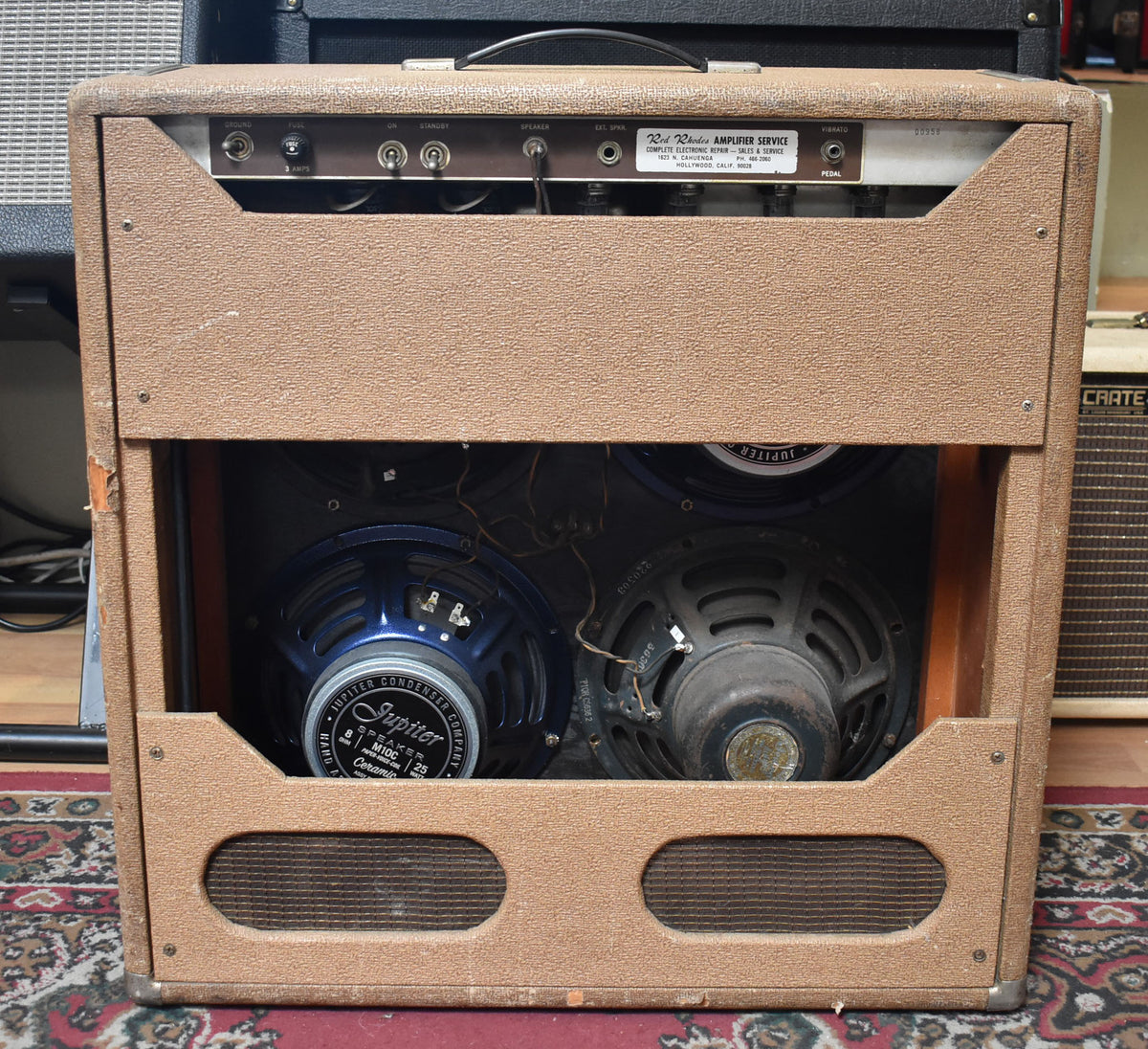 Rear view of a brown Fender amplifier with the back panel removed, showing two blue speakers and two dark speakers.