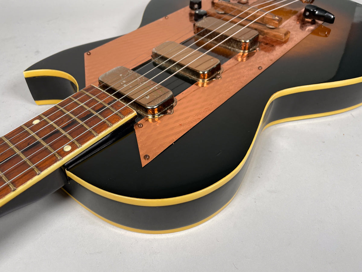 Close-up of the sunburst body and lower neck, showing the copper pickguard, two gold-covered pickups, and cream binding with light wear.