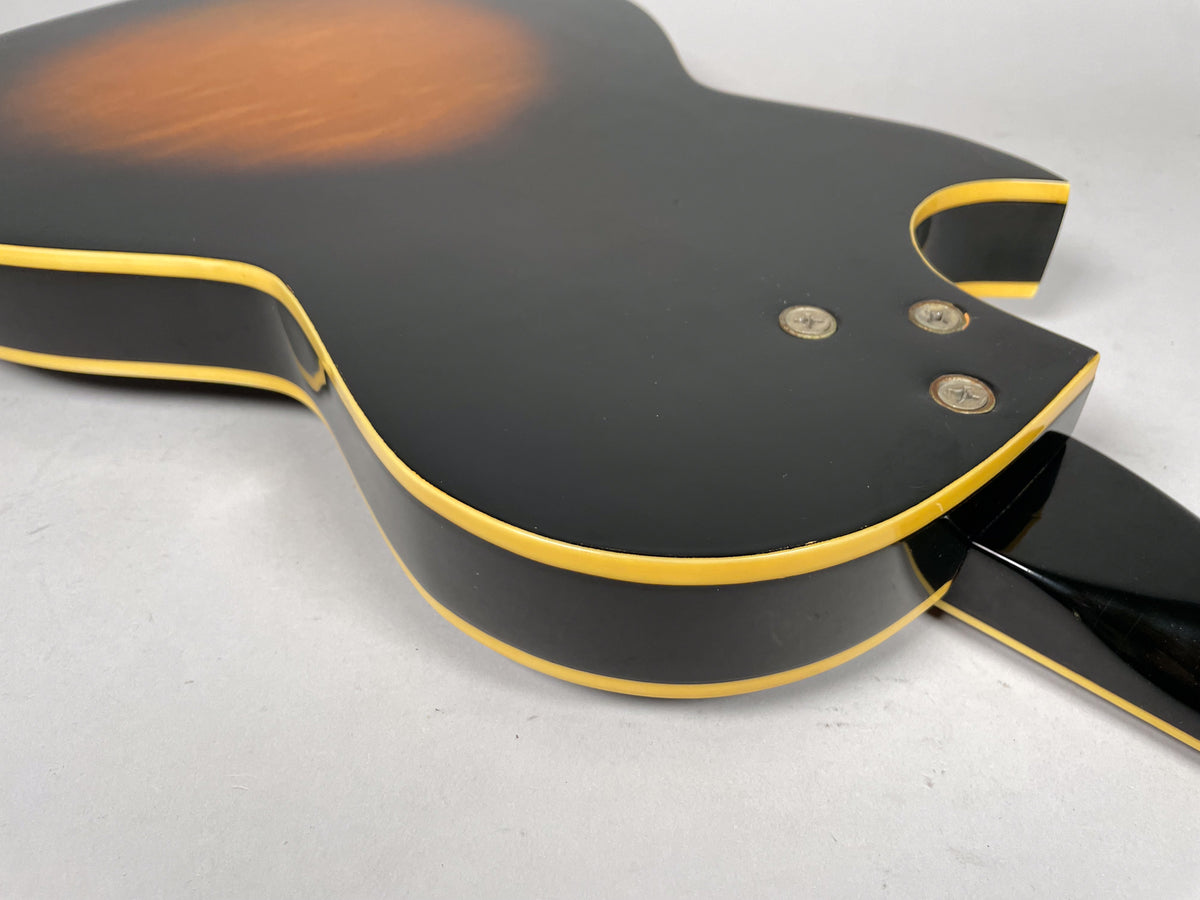 Close-up of the guitar's black back and sides with cream binding, showing three neck bolts and some finish wear near the neck joint.