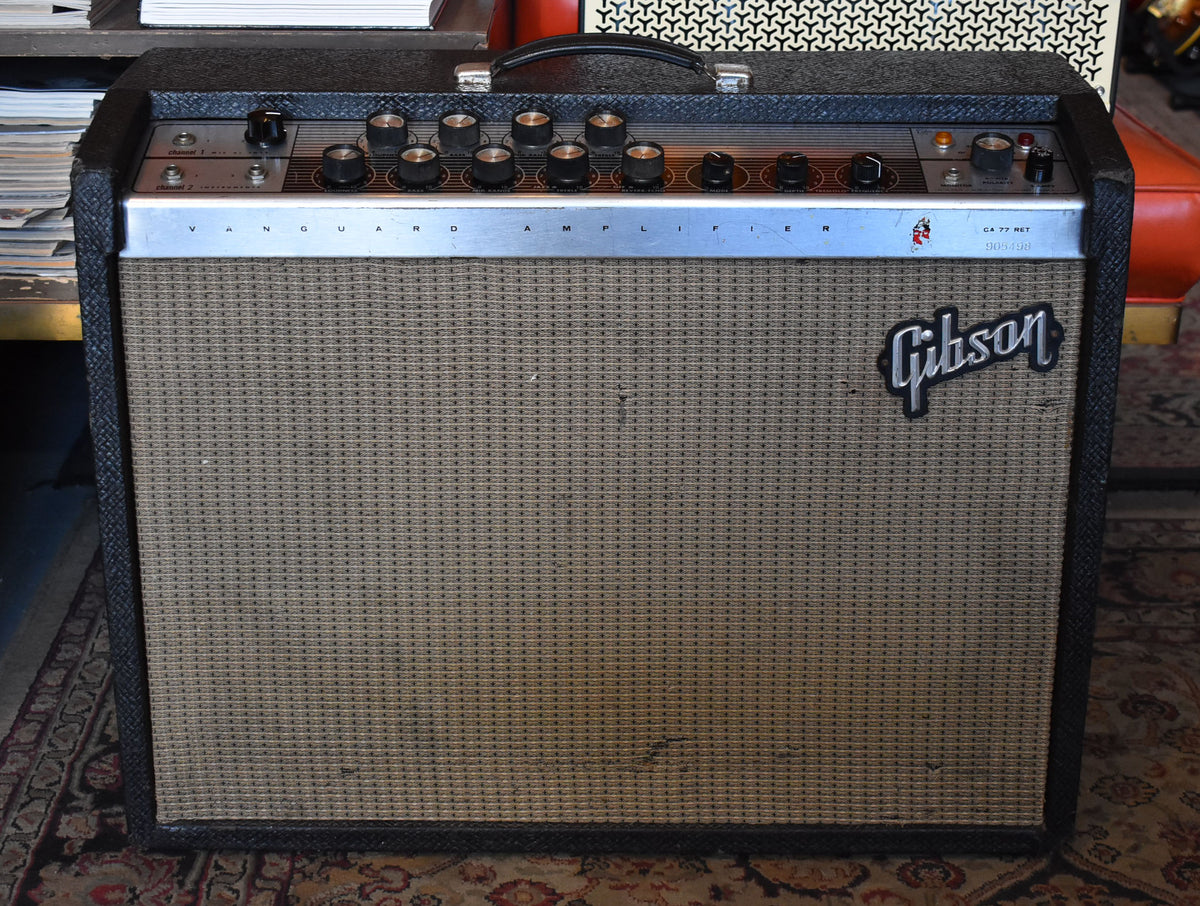 Front view of a vintage combo amp with black tolex, a tan grille cloth, and a silver control panel with 10 black knobs.
