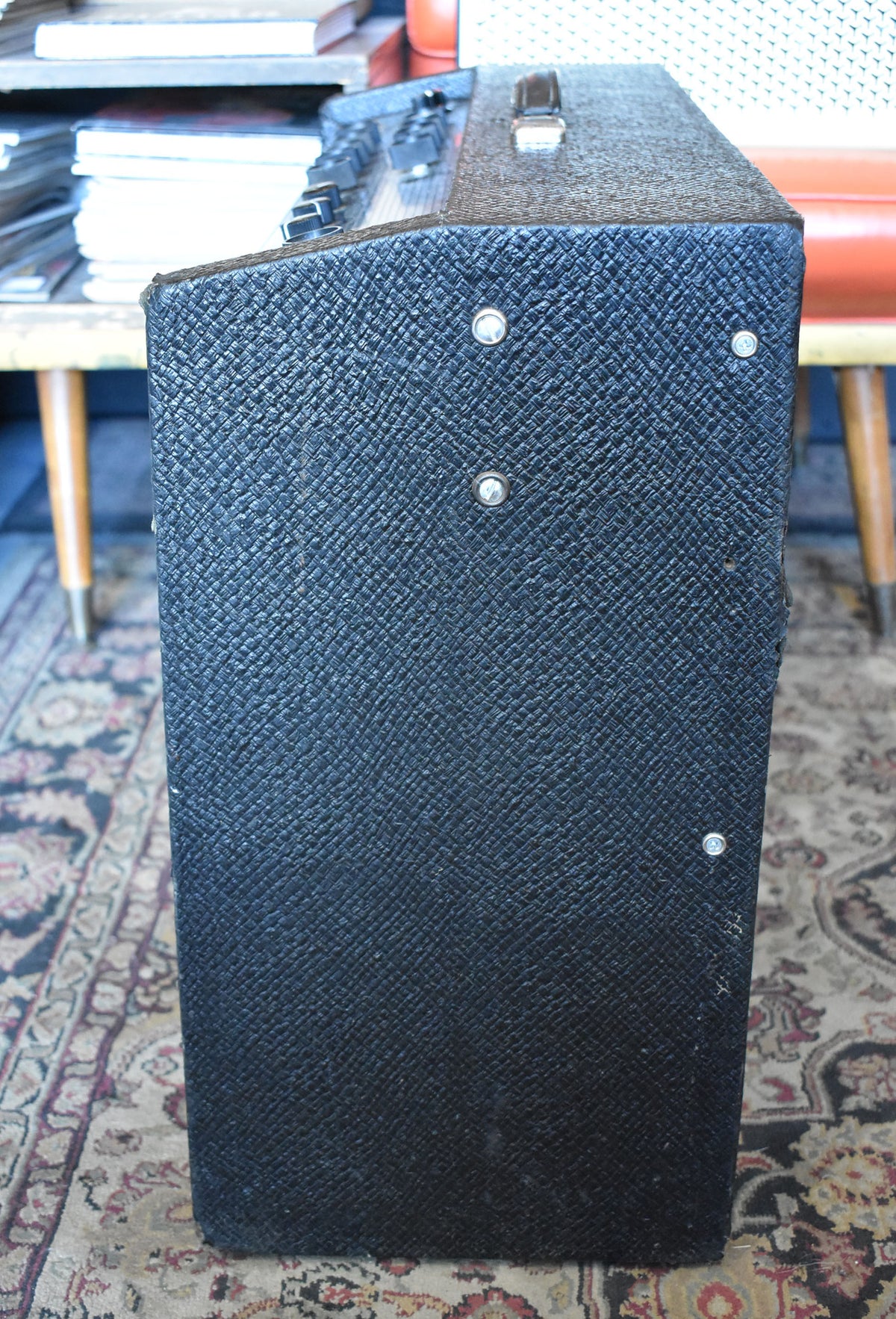 The amplifier's right side, covered in dark, textured tolex with some scuffs and four silver rivets, is shown from a low angle.