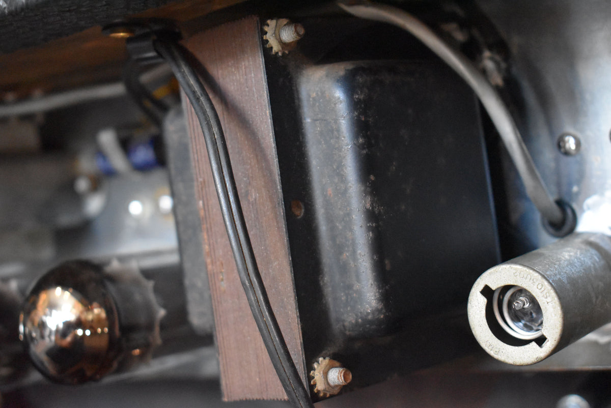 Close-up of the amplifier's internal components, showing a black transformer with visible rust and a clear tube socket.