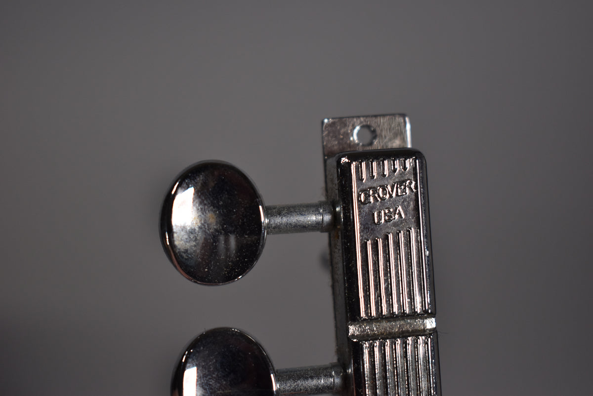 Close-up of two chrome tuning pegs with oval buttons, showing the ribbed casing of the tuner mechanism with "GROVER USA" stamped on it.