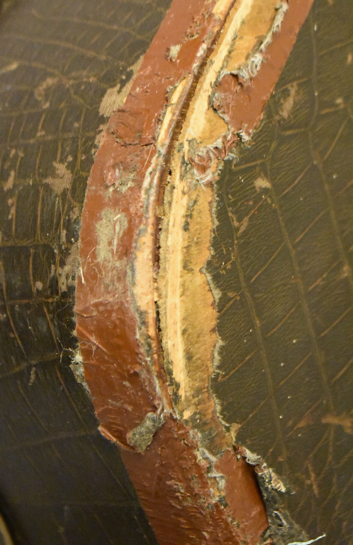 Close-up of the case's dark faux alligator exterior, showing a large, deep tear in the reddish-brown binding exposing the light wood underneath.