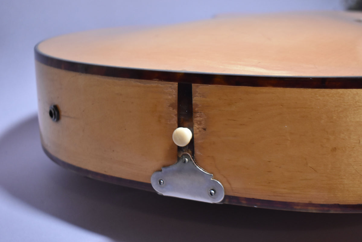 Close-up of the guitar's natural finish body, showing the input jack, a strap button, and a metal tailpiece bracket.