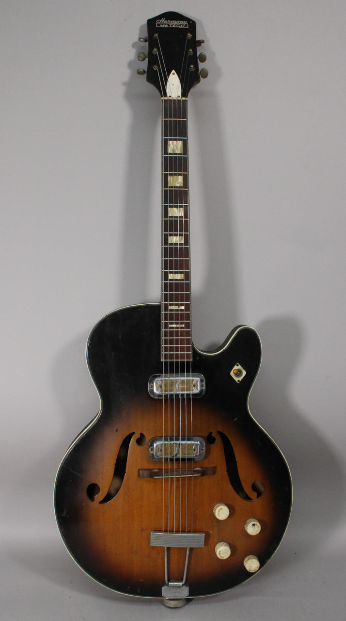 Full-front view of a sunburst hollow body electric guitar with two chrome pickups, f-holes, and four cream control knobs.
