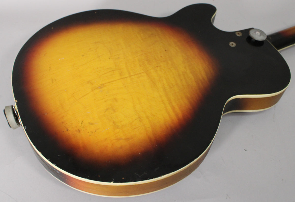 The guitar's sunburst back shows heavy finish checking, scratches, and wear, with a strap button and output jack visible.