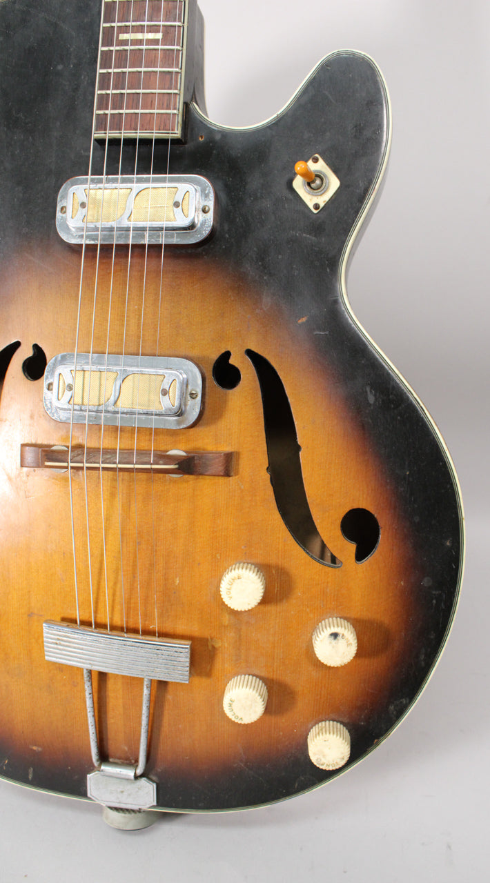 Close-up of the guitar's sunburst body, showing two gold foil pickups, f-holes, four cream "cupcake" knobs, and a trapeze tailpiece.