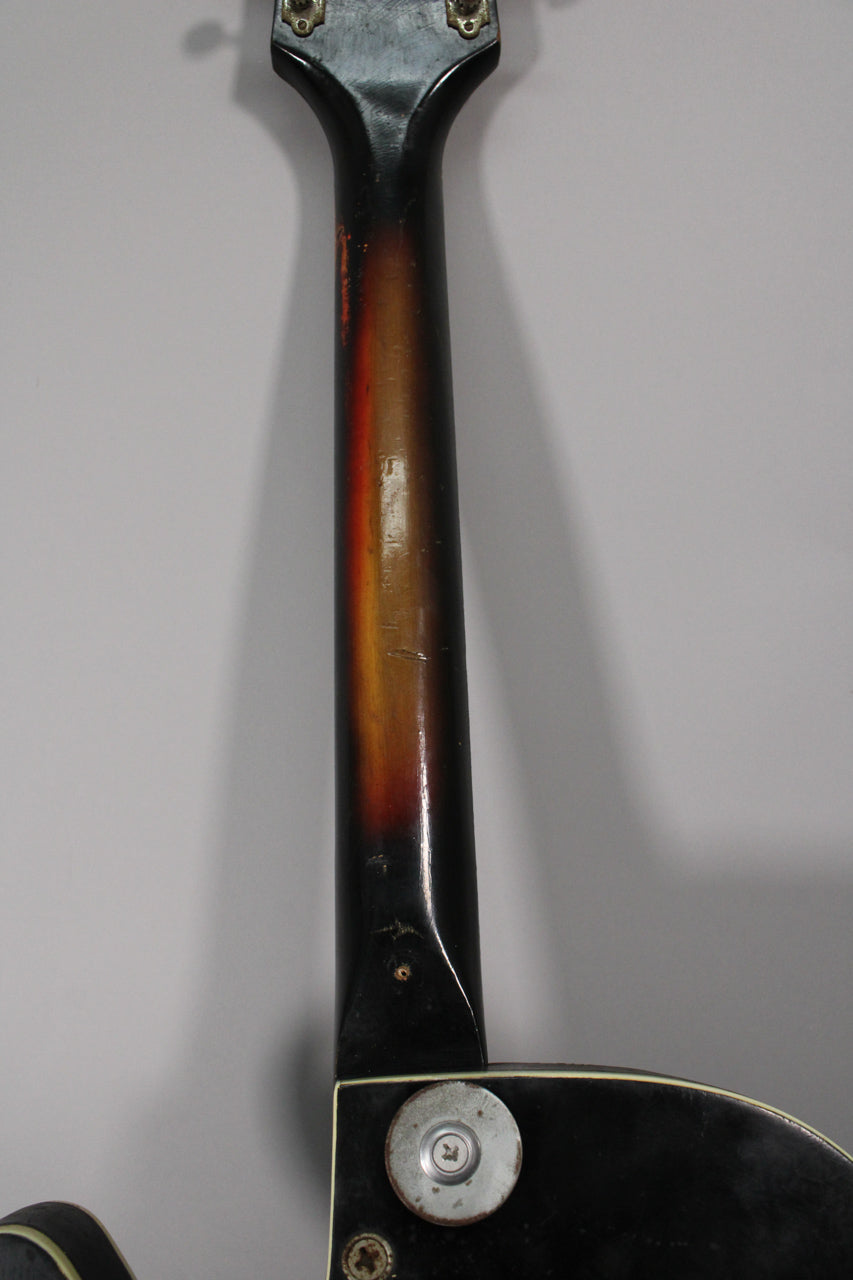 The back of the guitar's neck, showing a sunburst finish with significant wear and checking, connecting to the black body.