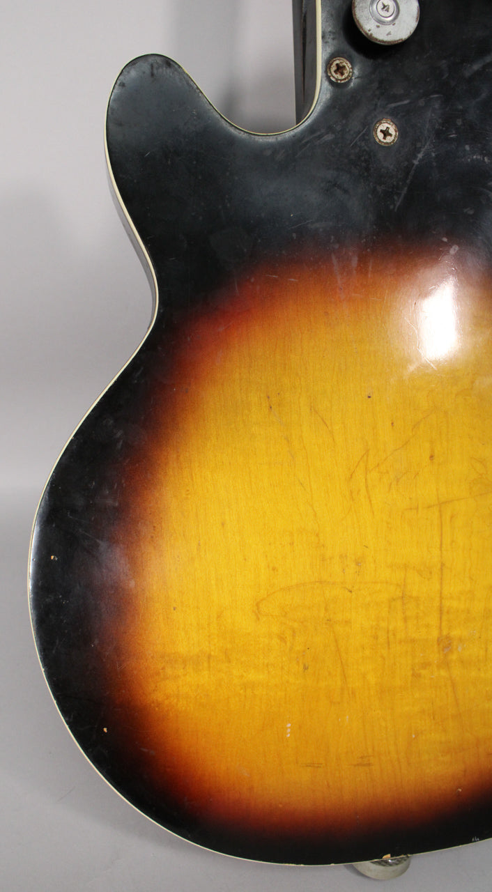 The guitar's lower bout and cutaway, showing a worn sunburst finish with many scratches and a visible strap button.