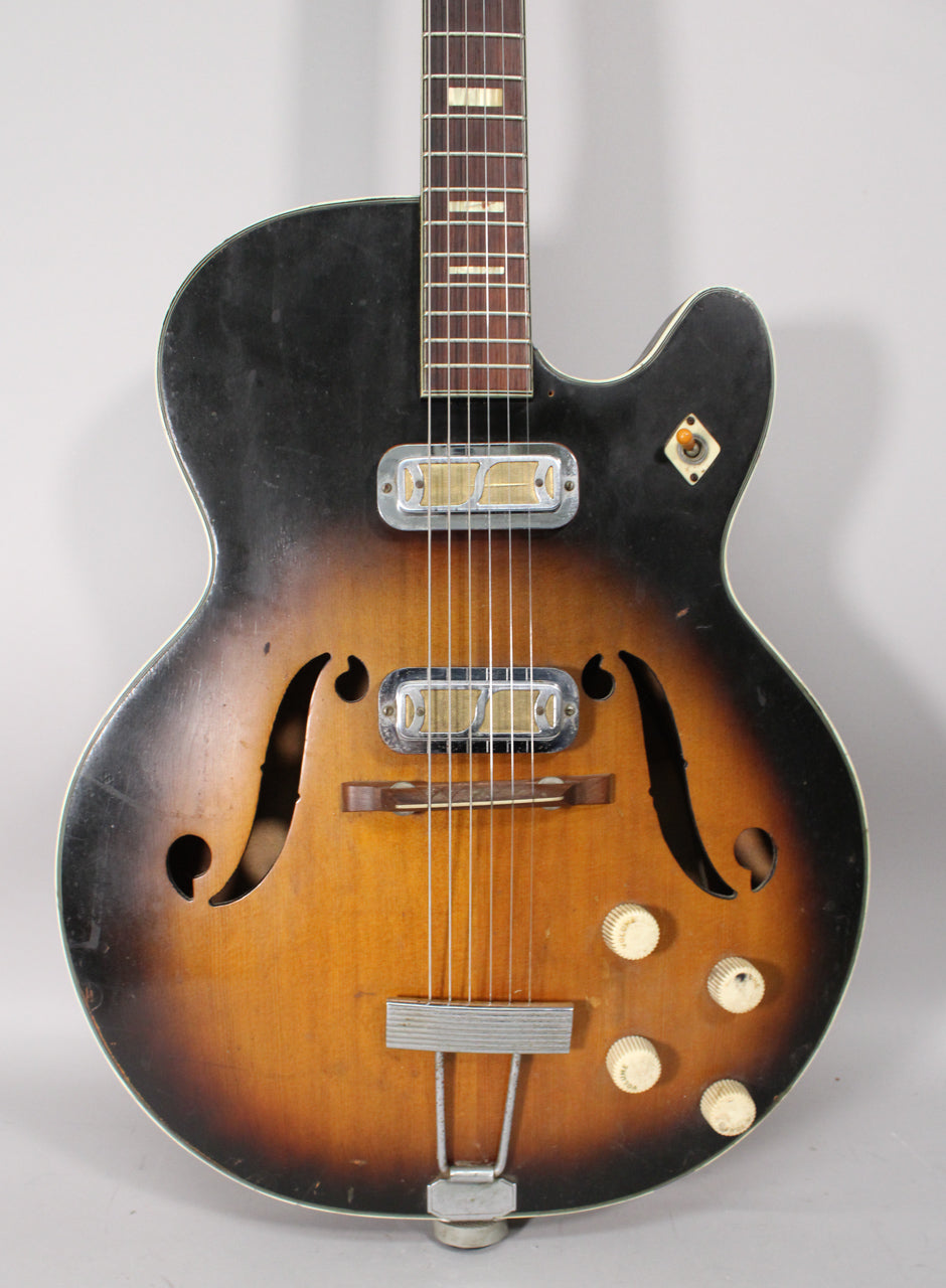 Full front view of a sunburst hollow body electric guitar with two gold foil pickups, f-holes, and four cream control knobs.