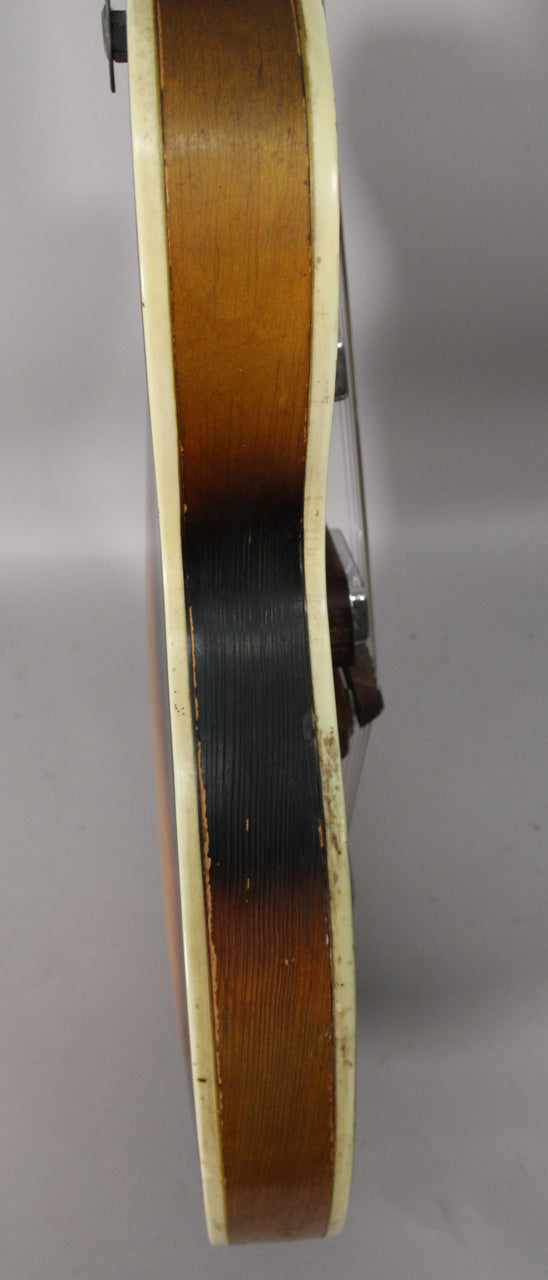 The guitar's thin, hollow body side is shown in a sunburst finish with heavy wear and binding separation along the cream edge.