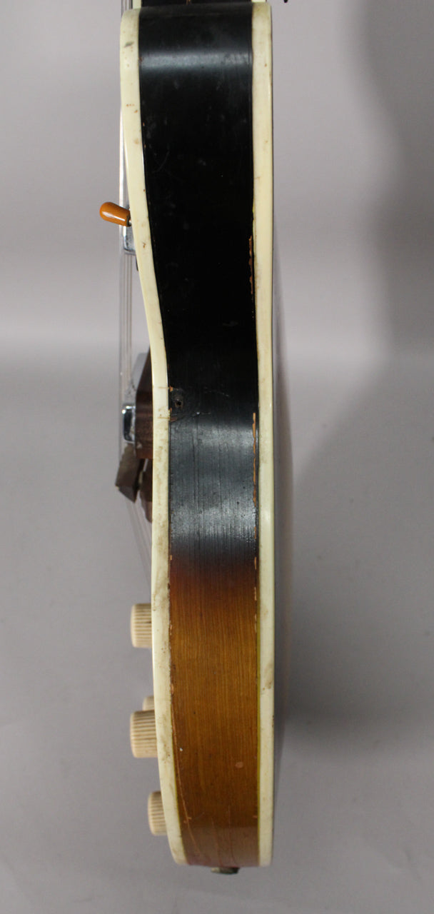 The guitar's side shows a black-to-sunburst finish, cream binding with visible wear, an orange switch tip, and three cream control knobs.