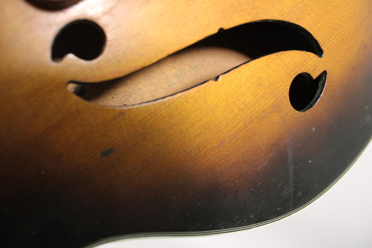 Close-up of the guitar's sunburst body, showing the upper f-hole and part of the lower, with visible wear and light scratches.