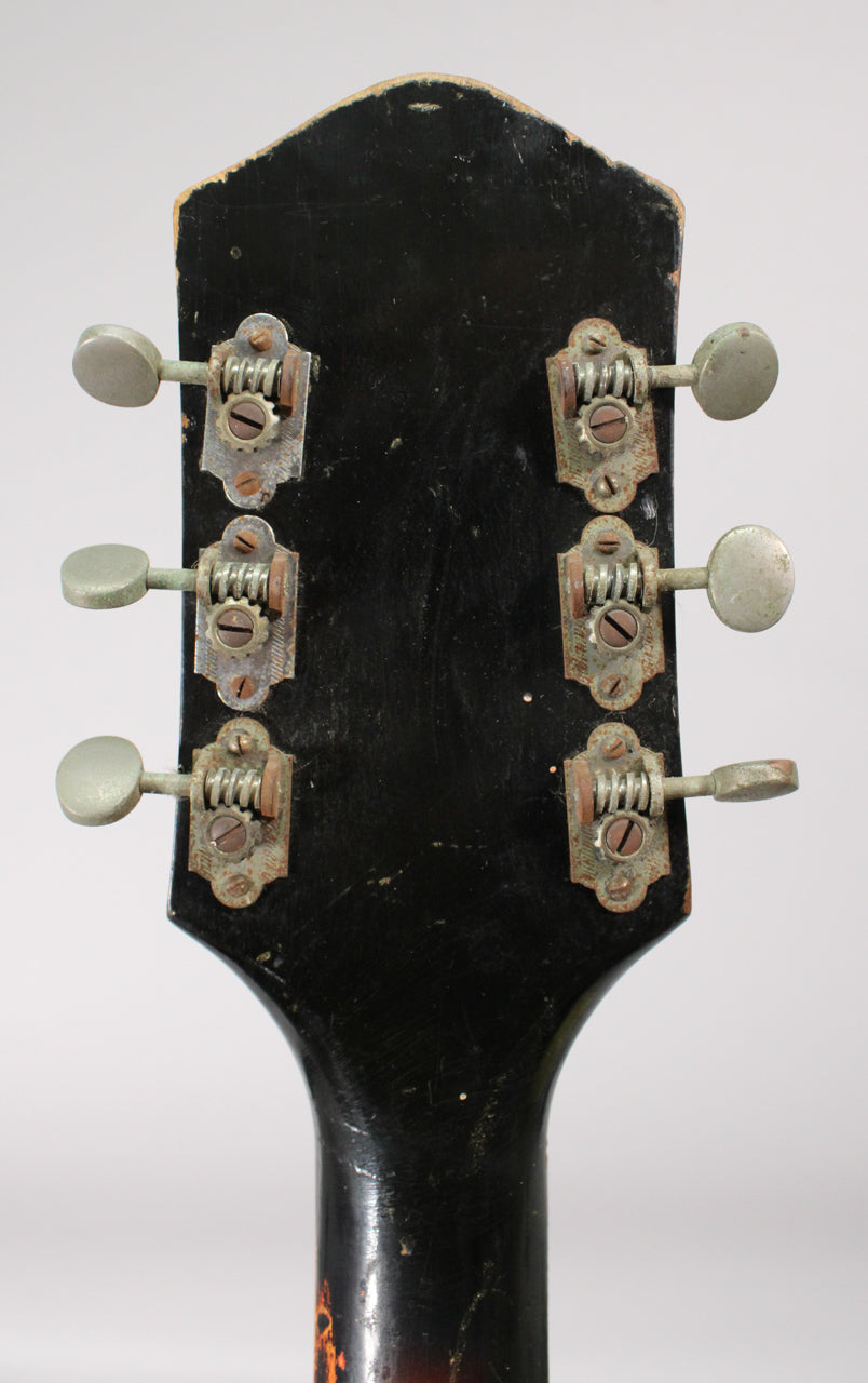 Rear view of the guitar's black headstock and neck, showing six rusty, tarnished tuning machines with worn, oval-shaped buttons.