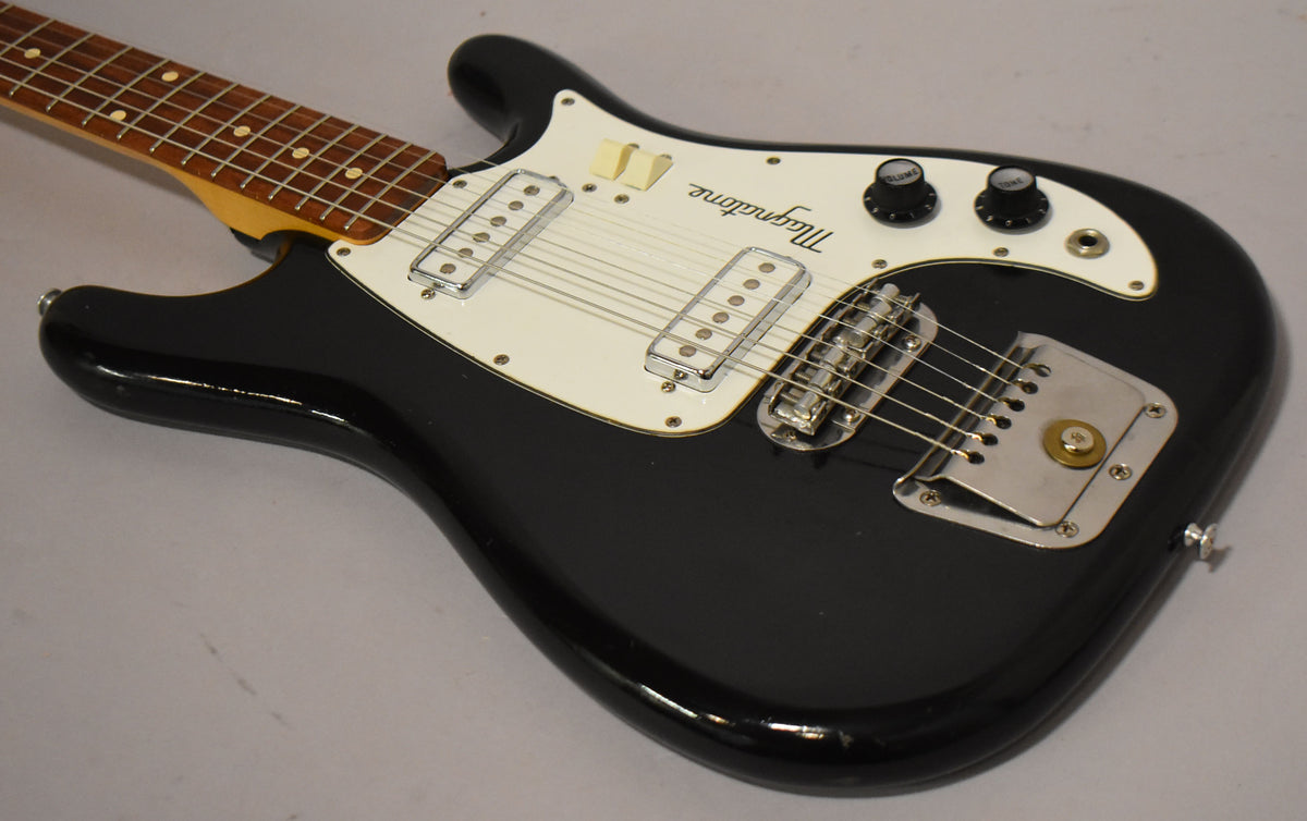 Black solidbody electric guitar, angled view of the body and neck, showing two chrome pickups, white pickguard, and vibrato tailpiece.