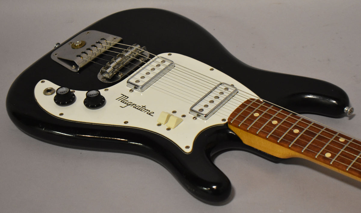 Black solidbody electric guitar, angled view of the body and neck, with a white pickguard, two single-coil pickups, and two black control knobs.